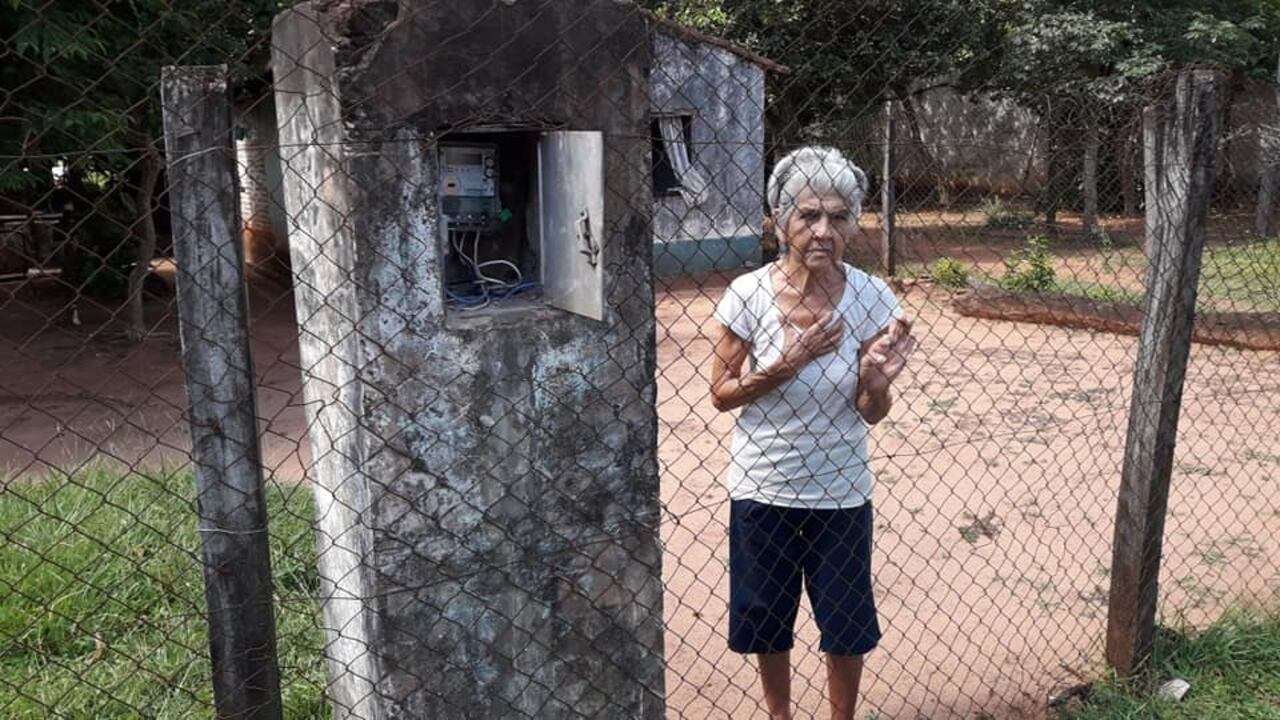 La abuelita posa al lado de su medidor de la ANDE.