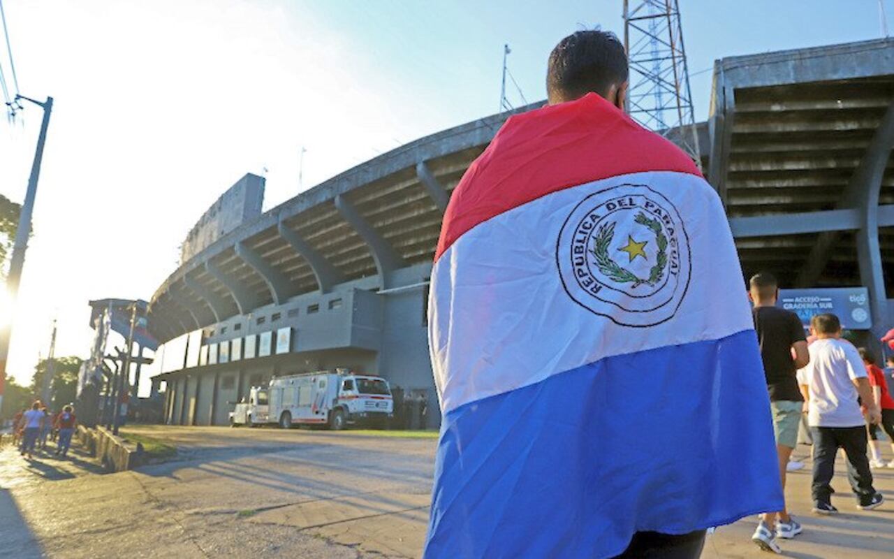 Fantástica imagen, el hincha albirrojo envuelto con la bandera y de fondo el estadio Defensores del Chaco.
