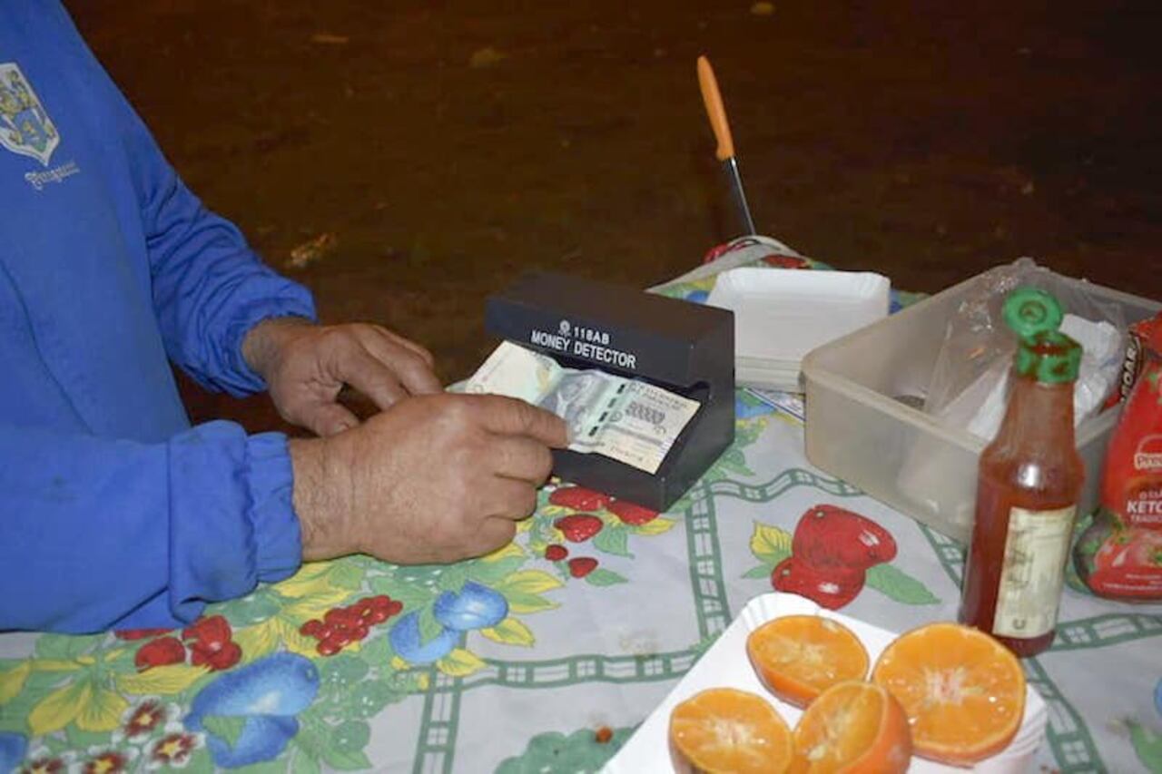 Aquí pasa un billete por la máquina que detecta si es falso o no. (Crédito: Benigno Bordón)